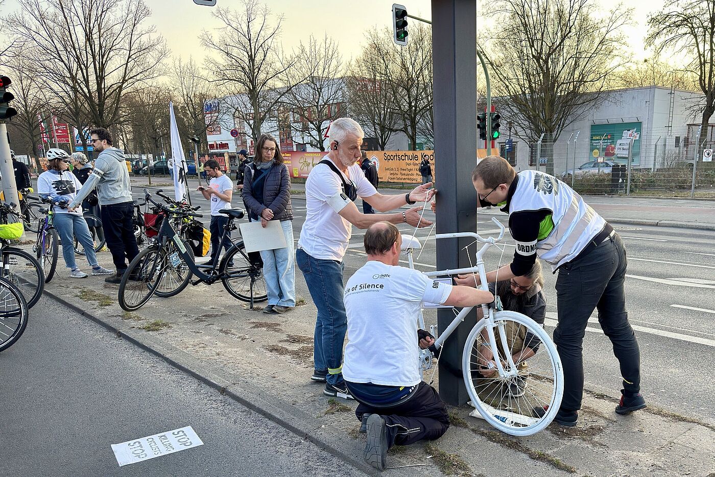 Ein weißes Geisterrad wird von vier Männern an der Straße aufgestellt