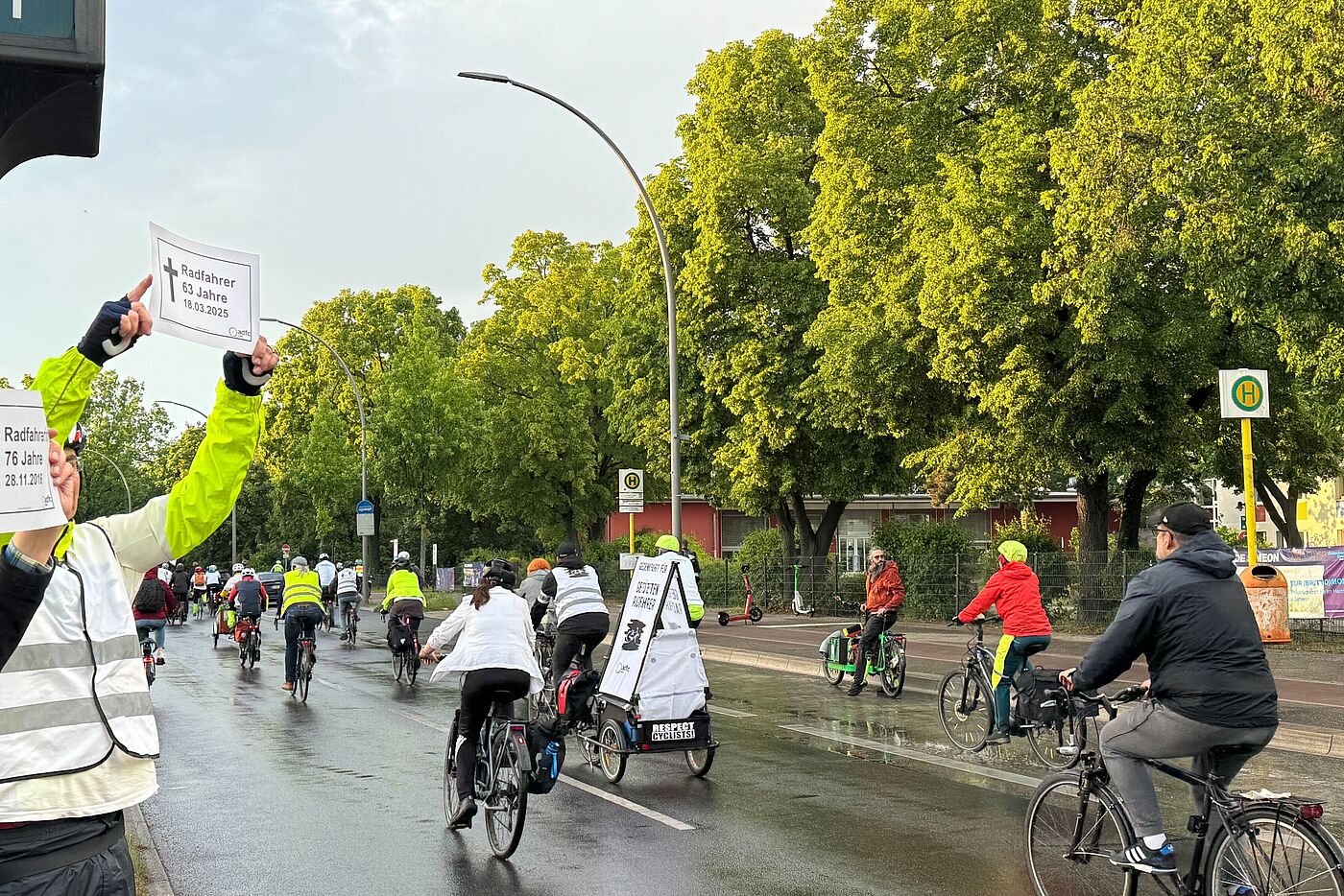 Ride of Silence 2026 Buckower Damm Menschen halten zwei weiße Gedenkschilder bei Fahrraddemonstration in die Luft