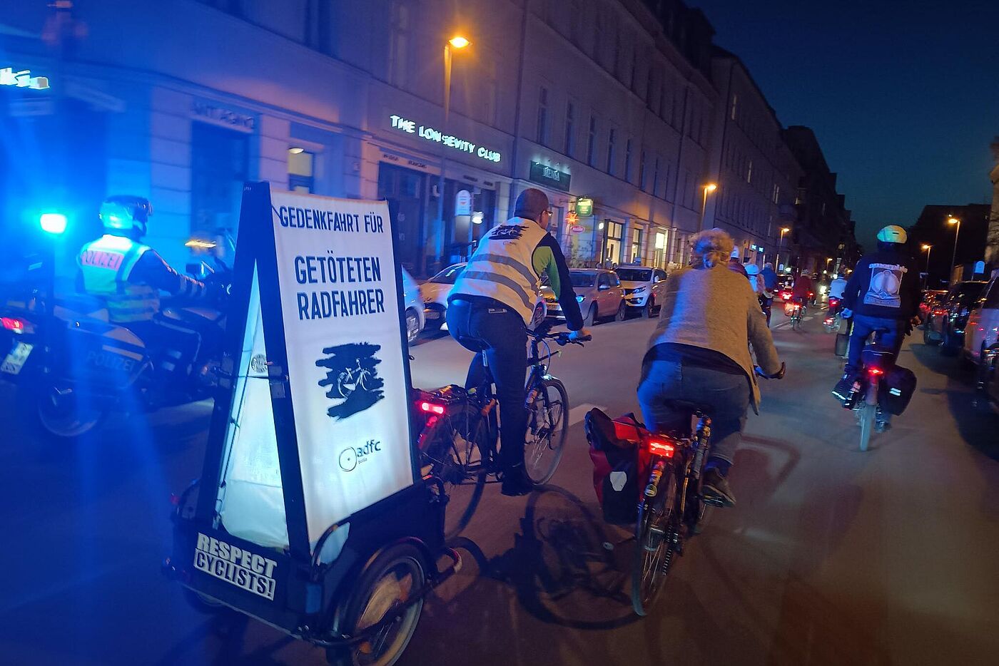 Radfahrende im Dunkeln mit leuchtenden Schild auf dem "Gedenkfahrt für getöteten Radfahrer" steht