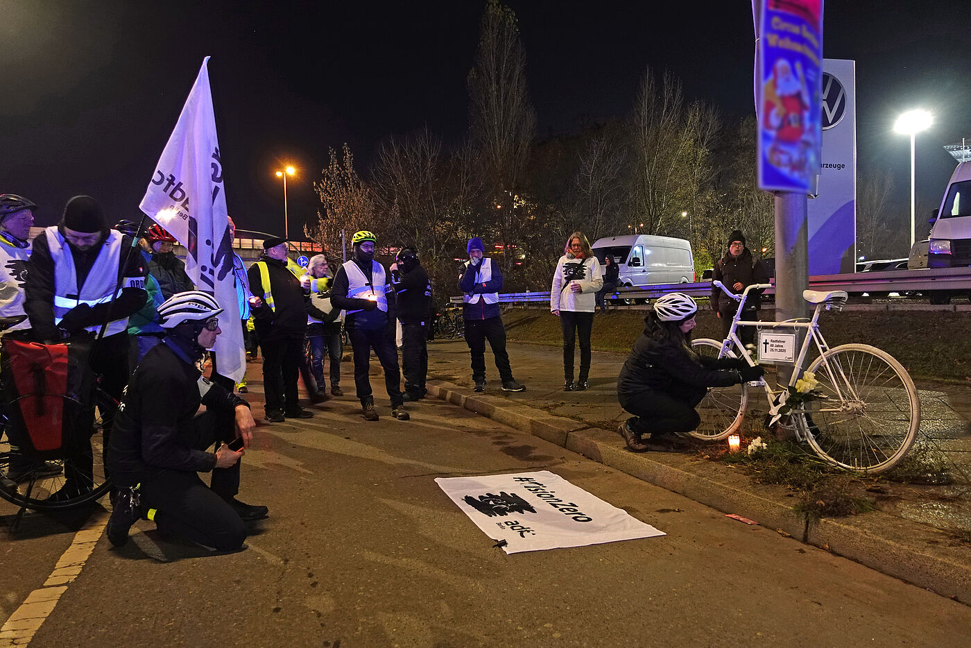 Geisterrad 1.12.2025 Tempelhof Menschen stehen bei einer Vision Zero Wahnwache auf der Straße vor einem weißen Fahrrad