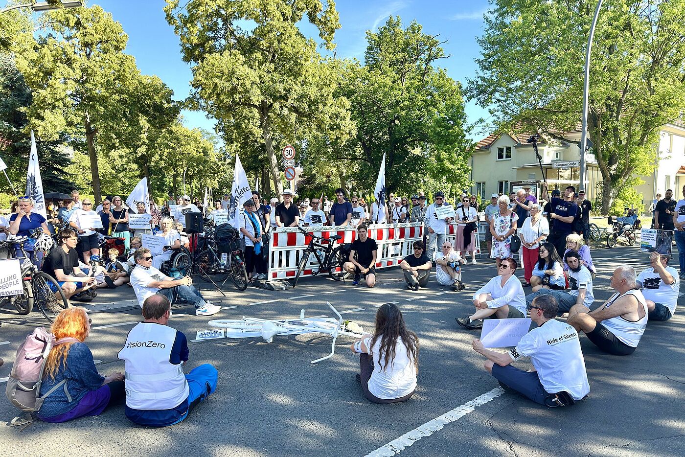 Geisterrad 30.06.2025 Menschen in weißen Vision Zero T-Shirts sitzen bei einer Mahnwache auf der Straße