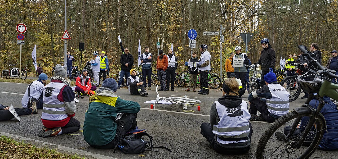 Menschen sitzen zur Mahnwache auf der Fahrbahn und gedenken eines getöteten Radfahrers